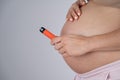 A pregnant woman smokes a vape. A girl holds an electronic cigarette against the background of her bare tummy. Copy Royalty Free Stock Photo