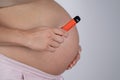 A pregnant woman smokes a vape. A girl holds an electronic cigarette against the background of her bare tummy. Copy Royalty Free Stock Photo