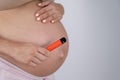 A pregnant woman smokes a vape. A girl holds an electronic cigarette against the background of her bare tummy. Copy Royalty Free Stock Photo