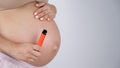 A pregnant woman smokes a vape. A girl holds an electronic cigarette against the background of her bare tummy. Copy Royalty Free Stock Photo