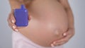 A pregnant woman smokes a vape. A girl holds an electronic cigarette against the background of her bare tummy.