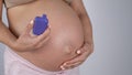 A pregnant woman smokes a vape. A girl holds an electronic cigarette against the background of her bare tummy.