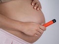 A pregnant woman smokes a vape. A girl holds an electronic cigarette against the background of her bare tummy. Royalty Free Stock Photo