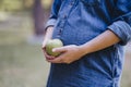 Pregnant woman snacking healthy with green apple