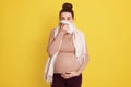 Pregnant woman sneezing, having cold, blowing runny nose, touching her belly with hand, feels bad, looks at camera, future mommy Royalty Free Stock Photo