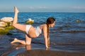 Pregnant woman in sports bra doing exercise in relaxation on yoga pose on sea Royalty Free Stock Photo