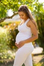 Pregnant woman standing in garden looking down at her belly Royalty Free Stock Photo