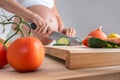 Pregnant woman standing at a kitchen counter with a wooden board