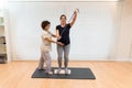 A pregnant woman standing on a proprioceptive trunk or wooden roller with an elastic band with physiotherapist