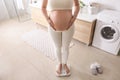 Pregnant woman standing on scales in bathroom Royalty Free Stock Photo