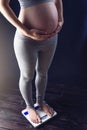 Pregnant woman standing on scales. Concept of weight loss and control during pregnancy Royalty Free Stock Photo