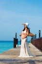 Pregnant woman is standing on a wooden pier hugging her stomach against the sea. Dominican Republic, the Caribbean Sea. Royalty Free Stock Photo