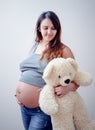 Pregnant woman stands holding a white teddy bear Royalty Free Stock Photo