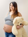 Pregnant woman stands holding a white teddy bear Royalty Free Stock Photo