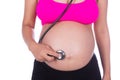 Pregnant woman with stethoscope listening belly to baby Royalty Free Stock Photo