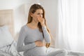 Pregnant woman feeling nauseous in bedroom