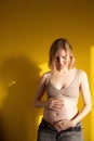 Pregnant woman stroking her tummy - over yellow background Royalty Free Stock Photo