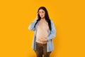 Pregnant woman suffering from acute headache, having migraine or high blood pressure, standing over yellow background