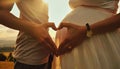 pregnant woman at sunset with man making heart from hands Royalty Free Stock Photo