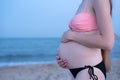 Pregnant woman in a swimsuit on the beach. Six months. Soft evening light. Belly closeup Royalty Free Stock Photo