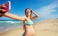 Pregnant woman take photo of her on sea beach Royalty Free Stock Photo