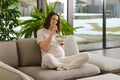Pregnant woman taking care of her child sitting on sofa in living room and eating vegetable salad Royalty Free Stock Photo