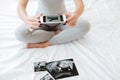 Pregnant woman taking pictures of ultrasound photos with cell phone