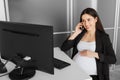 Pregnant woman talking on the phone in the office