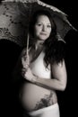 Pregnant woman with a tattoo looking holding an umbrella black Royalty Free Stock Photo