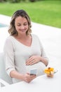 Pregnant woman texting and eating a fruit salad Royalty Free Stock Photo