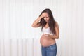 Pregnant woman with a thermometer in her bedroom. Pregnancy health and medcine contest. Illness, flu, allergy. 