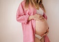 a pregnant woman third trimester in underwear and a pink shirt stands on a white background Royalty Free Stock Photo