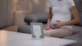 Pregnant woman touching belly and looking at photo of passed away relative Royalty Free Stock Photo