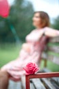 Pregnant woman touching bump whilst holding pink rose girl waiting