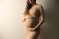 Pregnant woman touching her belly on beige background, closeup Royalty Free Stock Photo