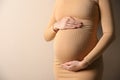 Pregnant woman touching her belly on beige background, closeup Royalty Free Stock Photo