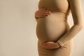 Pregnant woman touching her belly on beige, closeup. Space for text Royalty Free Stock Photo