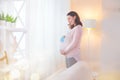 Pregnant woman touching her belly and playing with little baby shoes. Happy pregnant middle aged mother at home Royalty Free Stock Photo