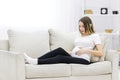 Pregnant woman touching her stomach on white sofa. Royalty Free Stock Photo