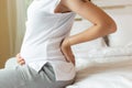 Pregnant woman touching tummy and suffering from back ache sitting on bed at home. Young attractive pregnant mother get back pain Royalty Free Stock Photo