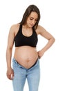 Pregnant woman trying to fit in tight jeans Royalty Free Stock Photo