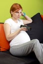 Pregnant woman with TV remote control Royalty Free Stock Photo