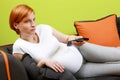 Pregnant woman with TV remote control Royalty Free Stock Photo