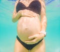 Pregnant woman underwater swimming in tropical sea. Healthy and active pregnancy. Young expecting mom on summer beach Royalty Free Stock Photo