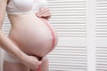 Pregnant woman in underwear measures belly using a measuring tape Royalty Free Stock Photo