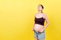 Pregnant woman in unzipped jeans showing her abdomen at colorful background with copy space Royalty Free Stock Photo