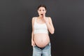 Pregnant woman in unzipped jeans showing her abdomen at colorful background with copy space Royalty Free Stock Photo