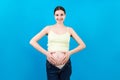 Pregnant woman in unzipped jeans showing her abdomen at colorful background with copy space Royalty Free Stock Photo