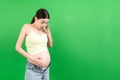 Pregnant woman in unzipped jeans showing her abdomen at colorful background with copy space Royalty Free Stock Photo