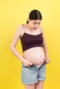 pregnant woman in unzipped jeans showing her naked belly at colorful background with copy space. Baby expecting concept Royalty Free Stock Photo